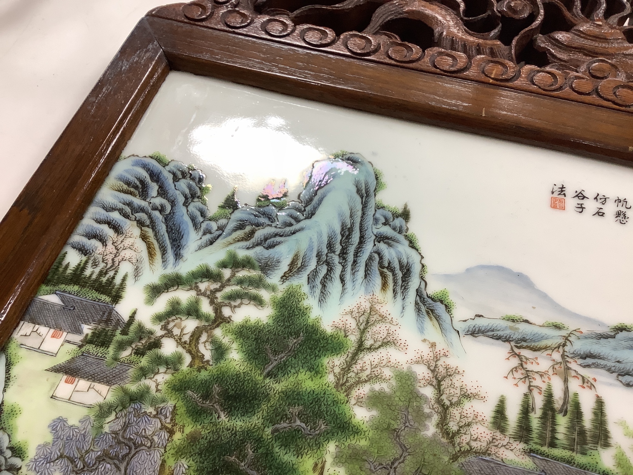 A 20th century Republic period porcelain plaque decorated in coloured enamels with landscape scene, inscription mark 24 x 38cm in carved frame